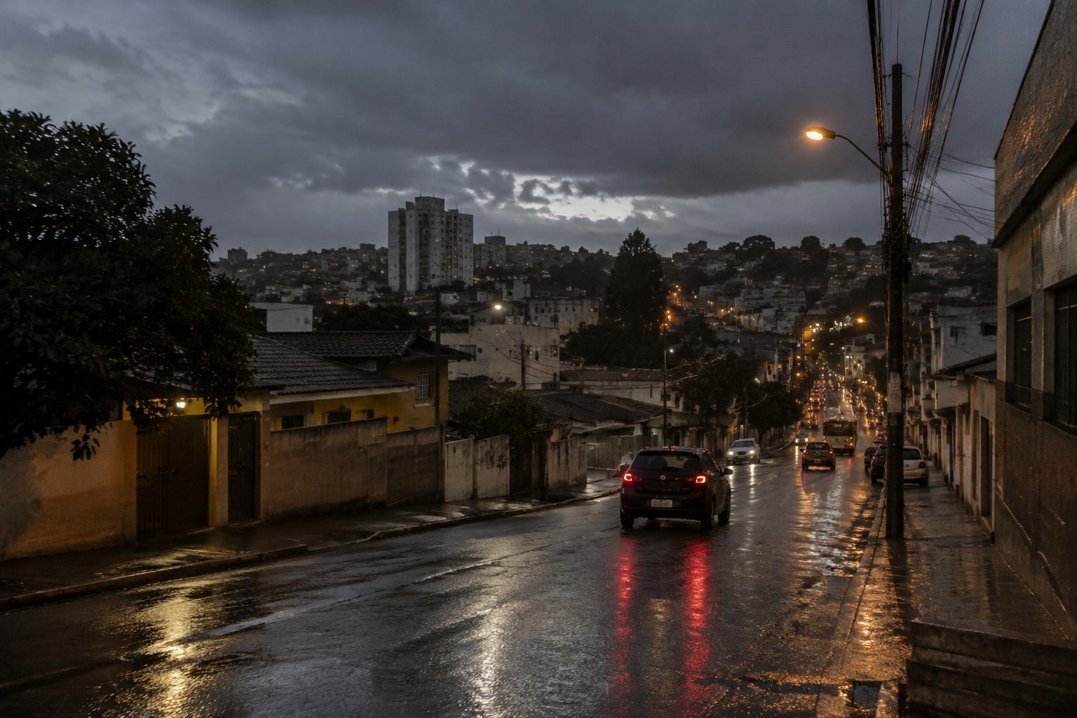 Rua urbana em Minas Gerais com asfalto molhado, iluminação ao entardecer e nuvens escuras de chuva.